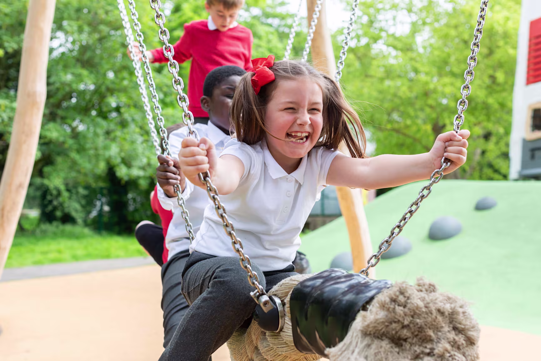 Children swinging on a cocowave swing on an inclusive playground