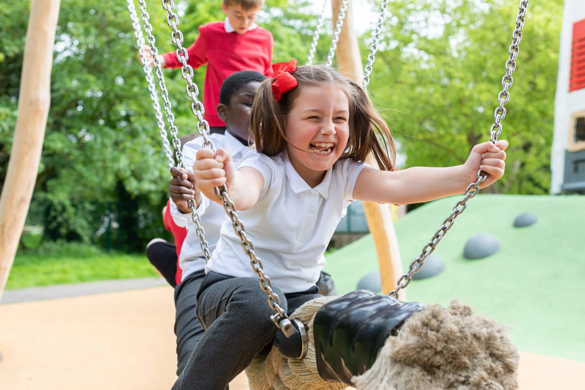 Children swinging on a cocowave swing on an inclusive playground