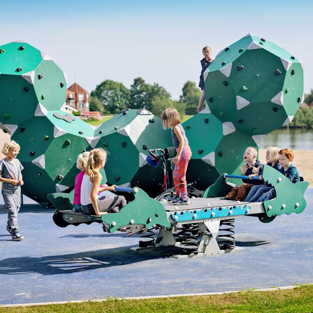 Kinder schwingen auf einer Tampenschaukel auf einem integrativen Spielplatz