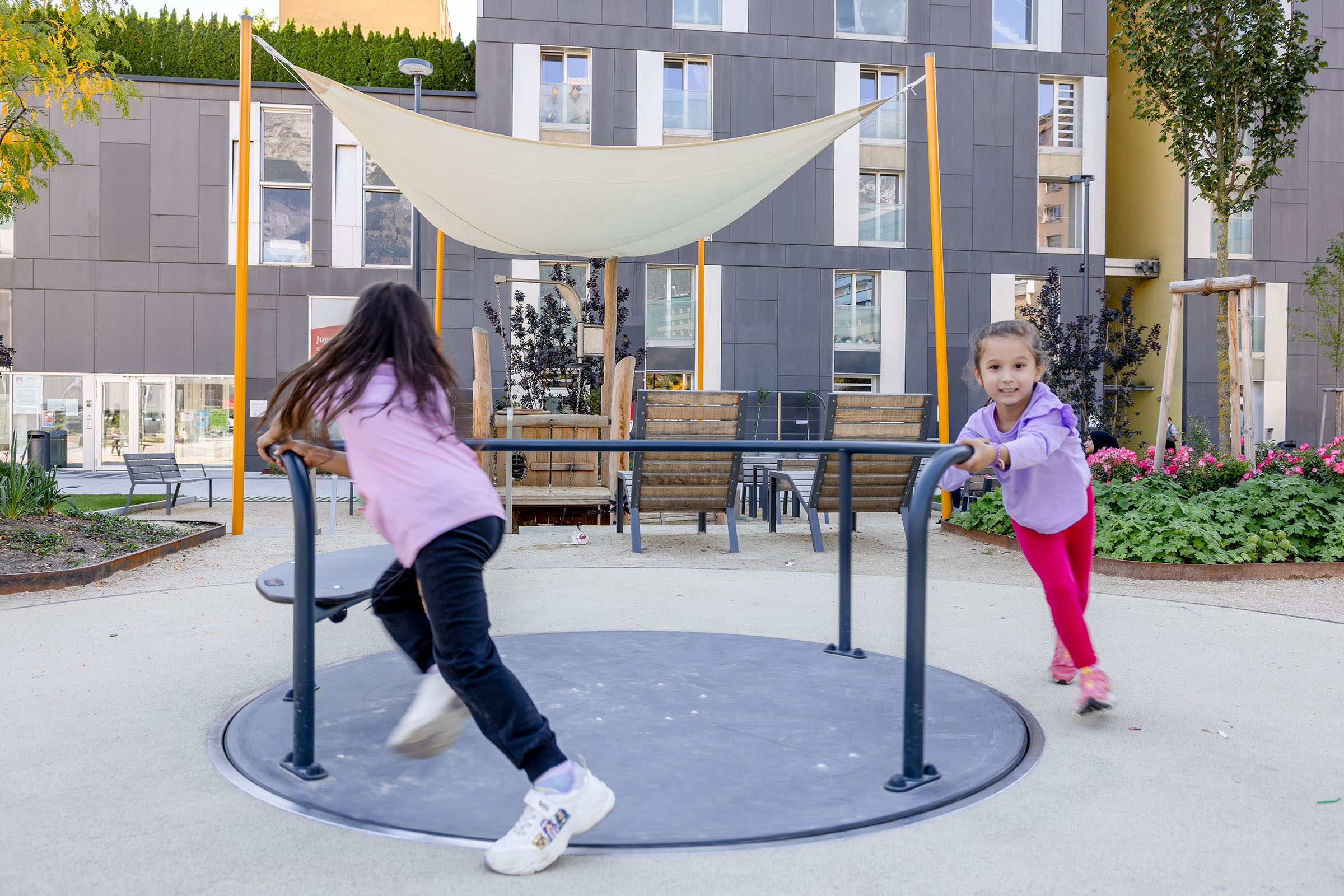 Zwei Mädchen spielen an einem Karussell in Innsbruck, Österreich