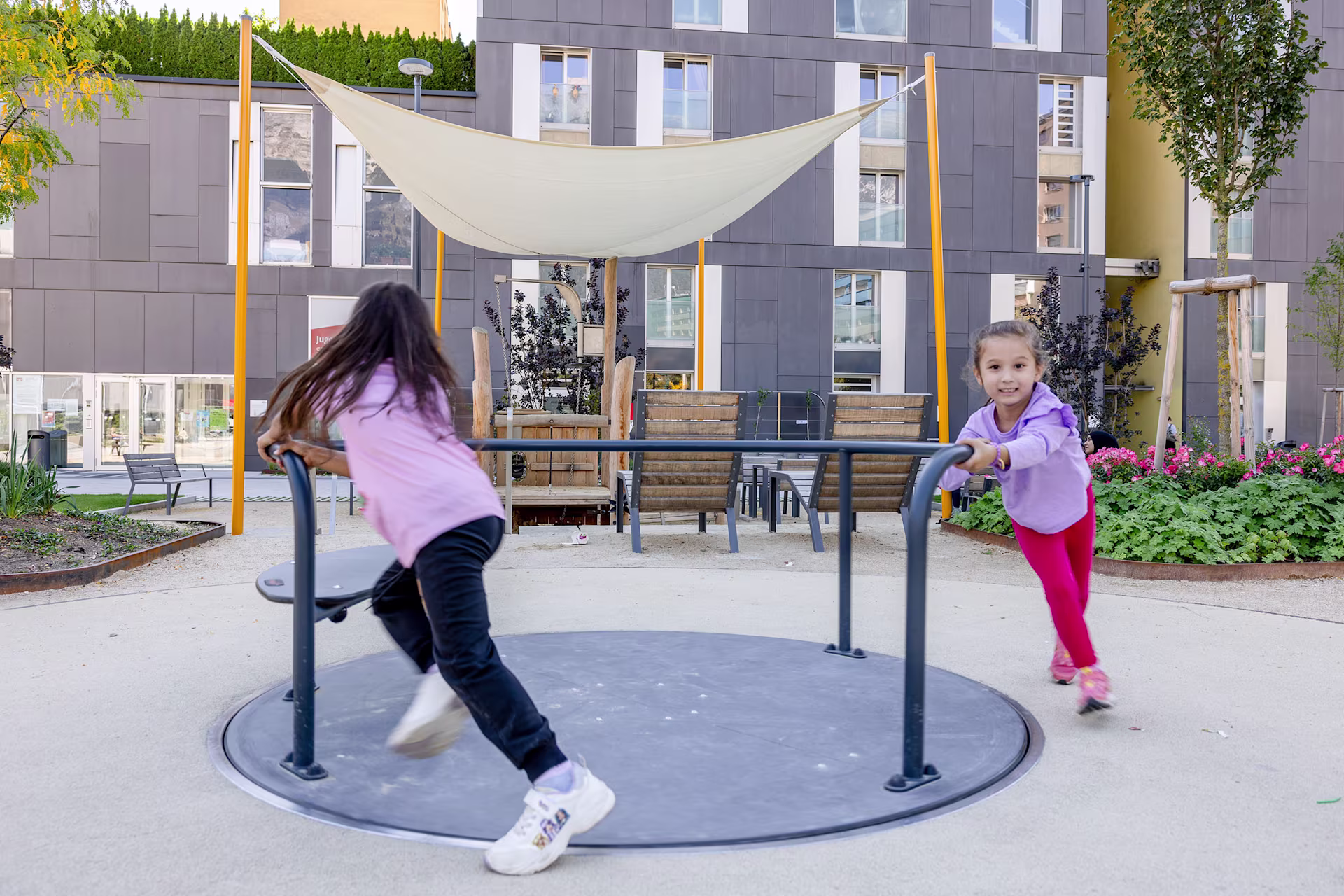 Zwei Mädchen spielen an einem Karussell in Innsbruck, Österreich