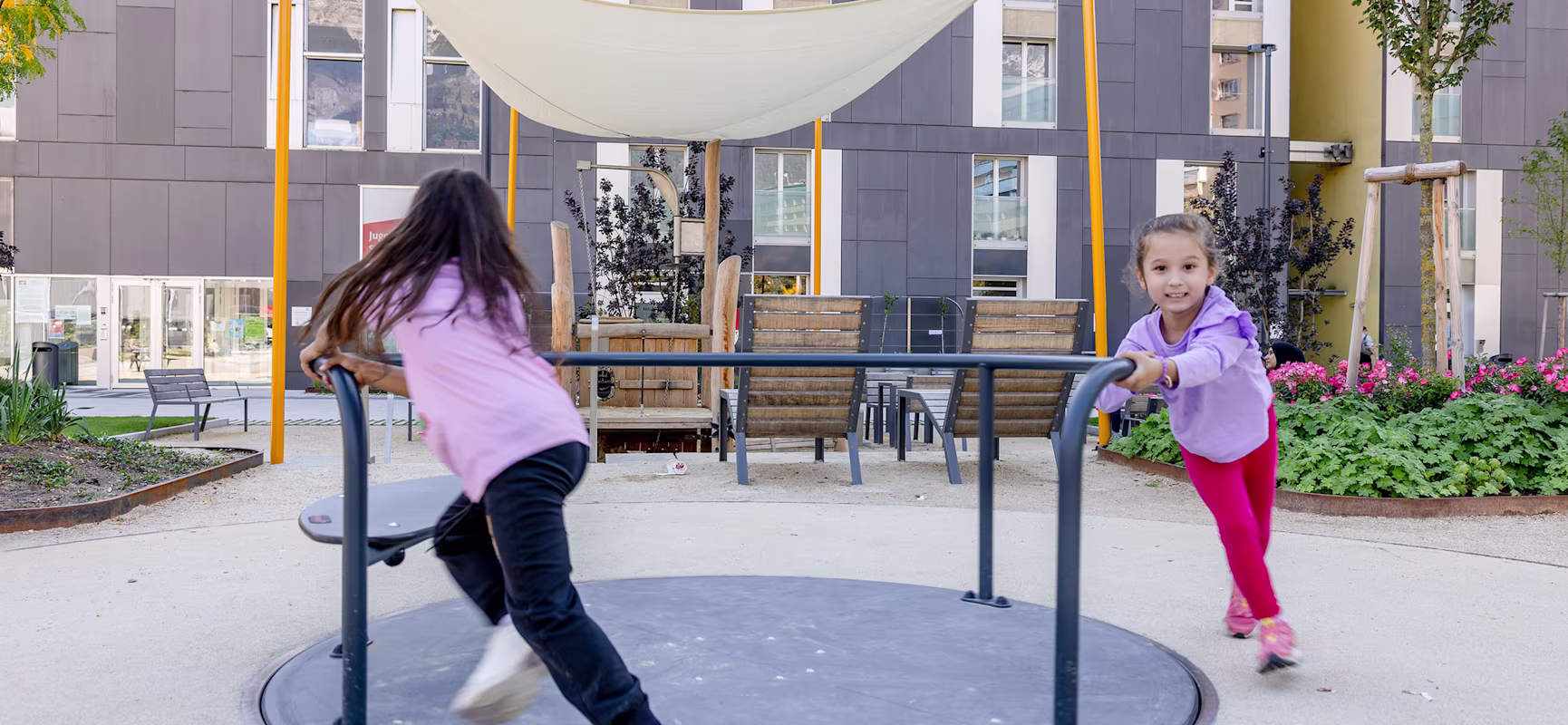 Zwei Mädchen spielen an einem Karussell in Innsbruck, Österreich