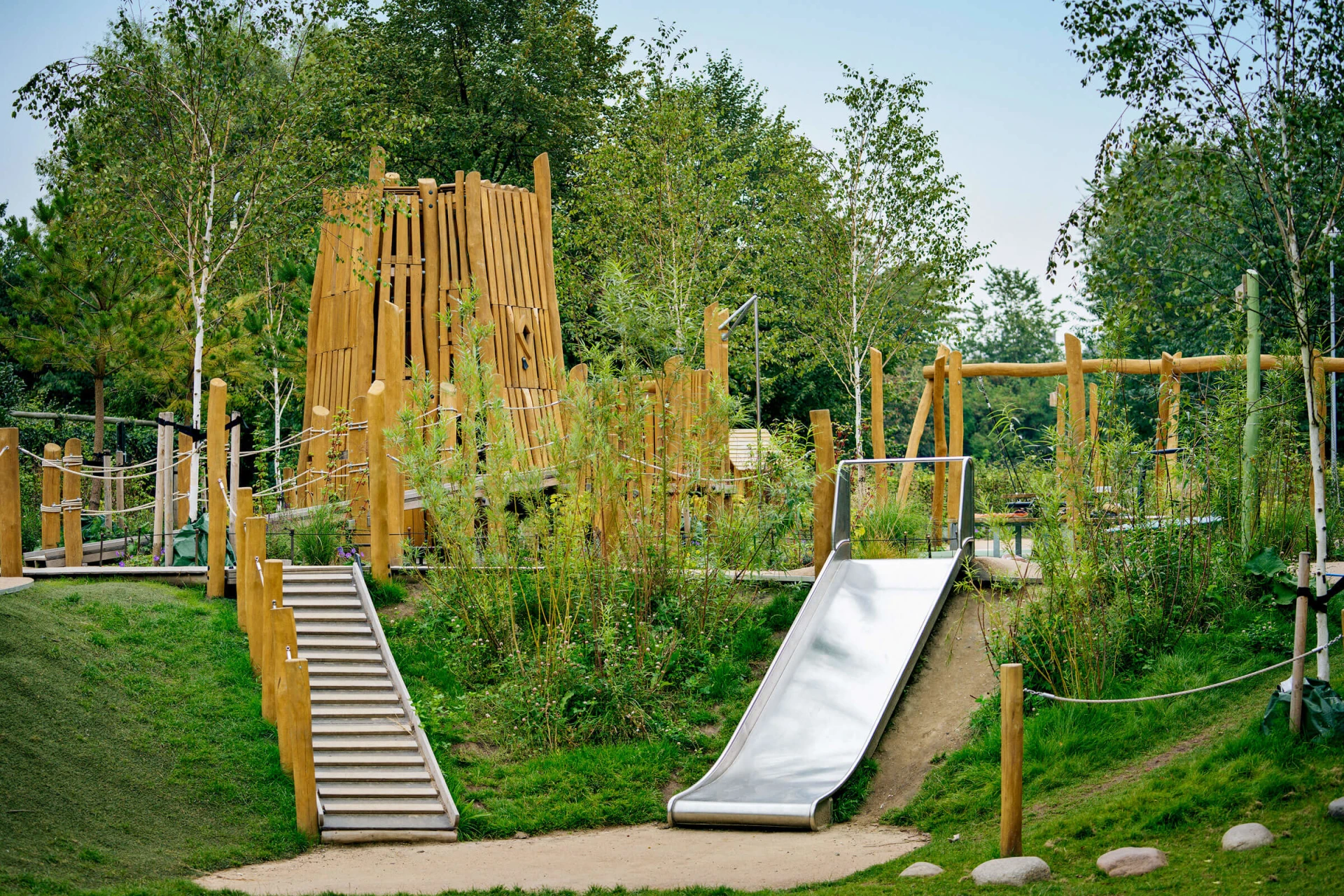 specialdesignet trælegeplads med legetårn og rutsjebaner i en park