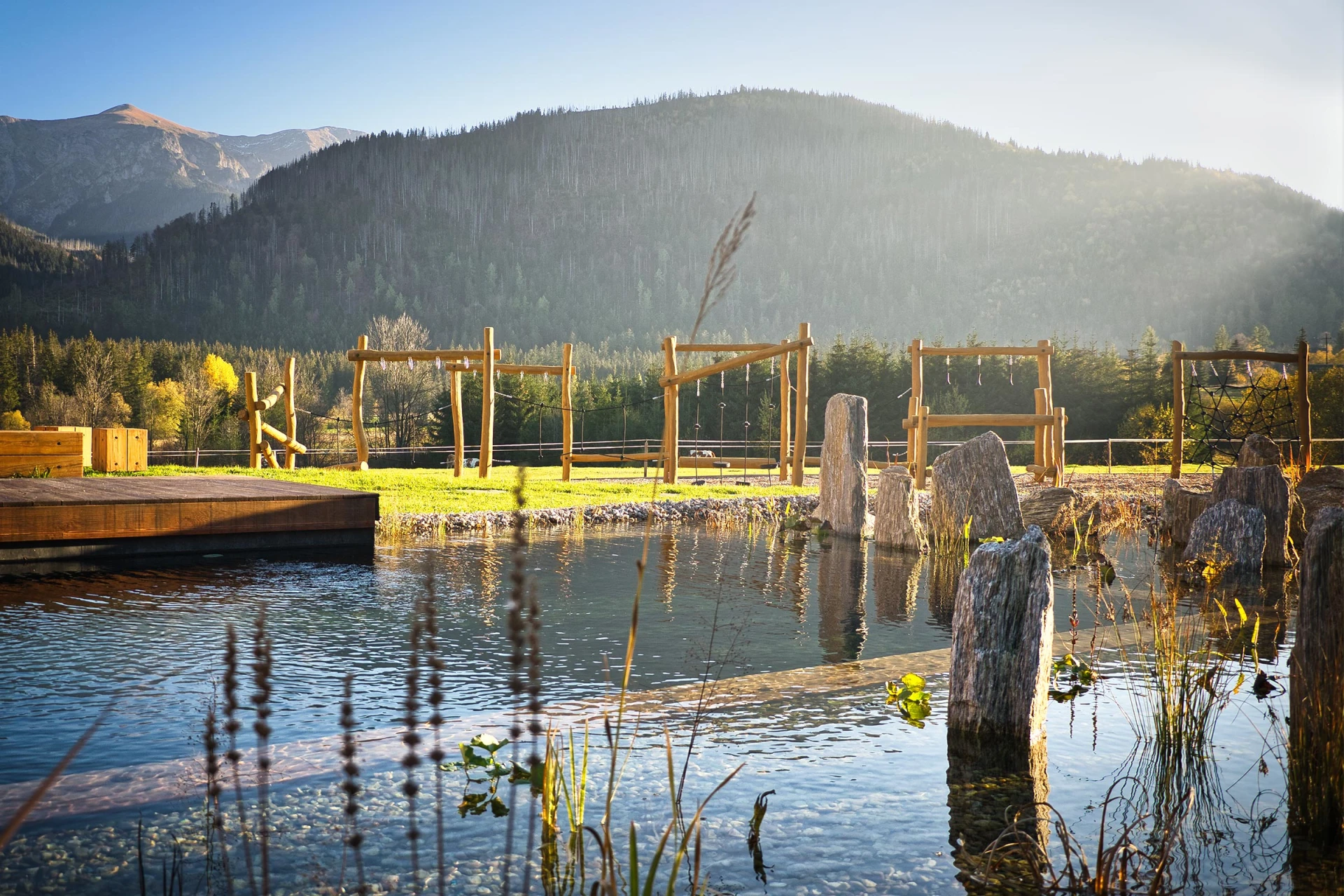 A pond with wooden playground and a mountain in the background.