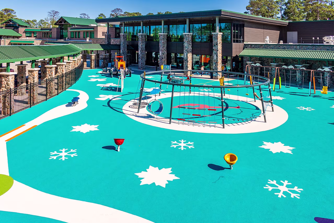 Wide shot of a playground, showcasing the ice-blue, winter-themed poured-in-place (PIP) surfacing, which features snowflakes and other winter-themed elements.