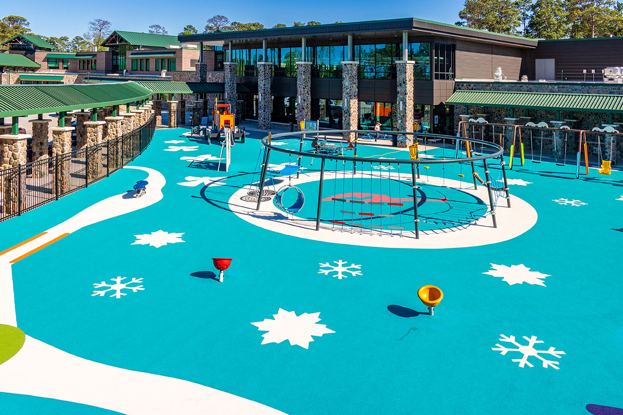 Wide shot of a playground, showcasing the ice-blue, winter-themed poured-in-place (PIP) surfacing, which features snowflakes and other winter-themed elements.