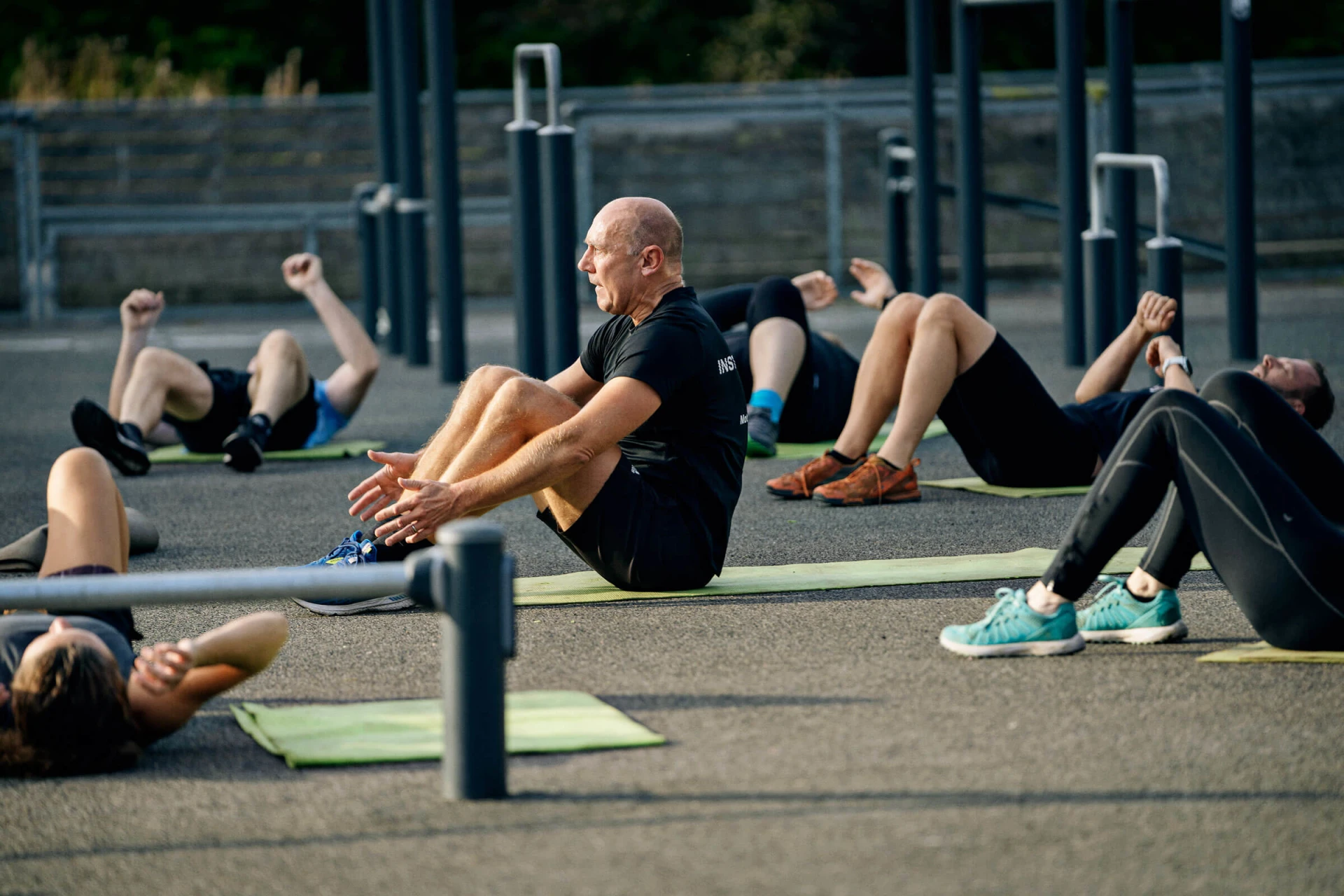 En gruppe mennesker, der træner i en udendørs gymnastiksal i en park.