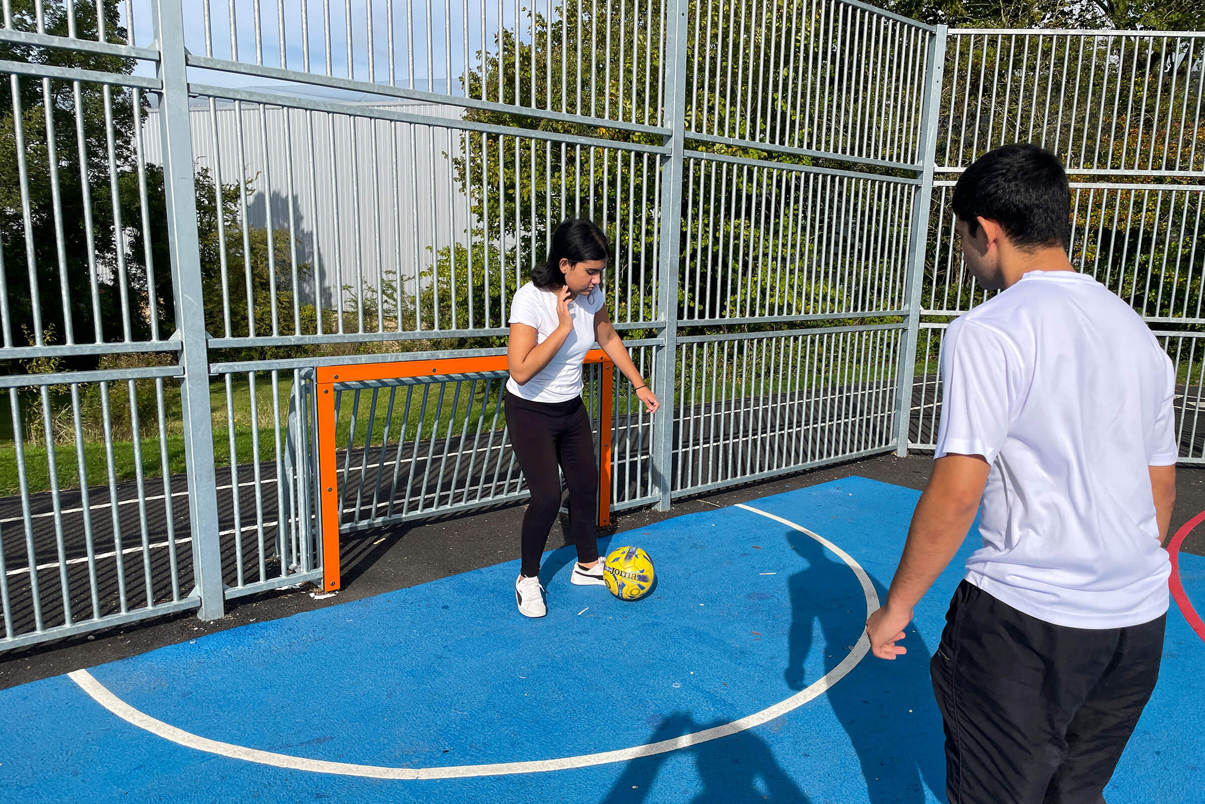 Tweens playing soccer on a multi court
