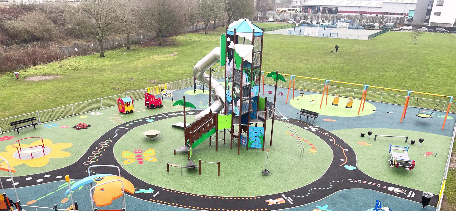 a colourful playground with a giant play structure and toddler play equipment