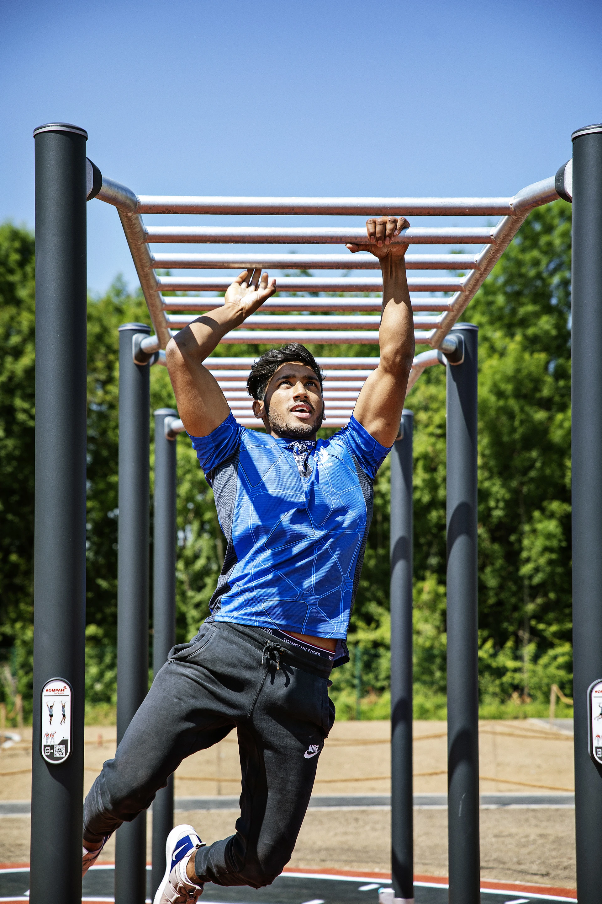 ung man går armgång på hinderbana i utegym