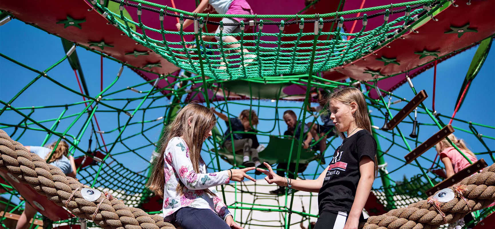 Deux filles assises sur une aire de jeux de cordes