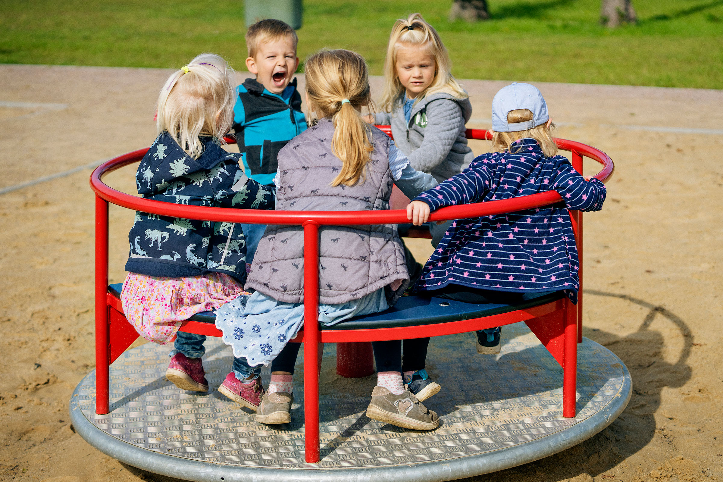 Kitakinder spielen auf einem Spielplatzkarussell in Ihlow, Deutschland