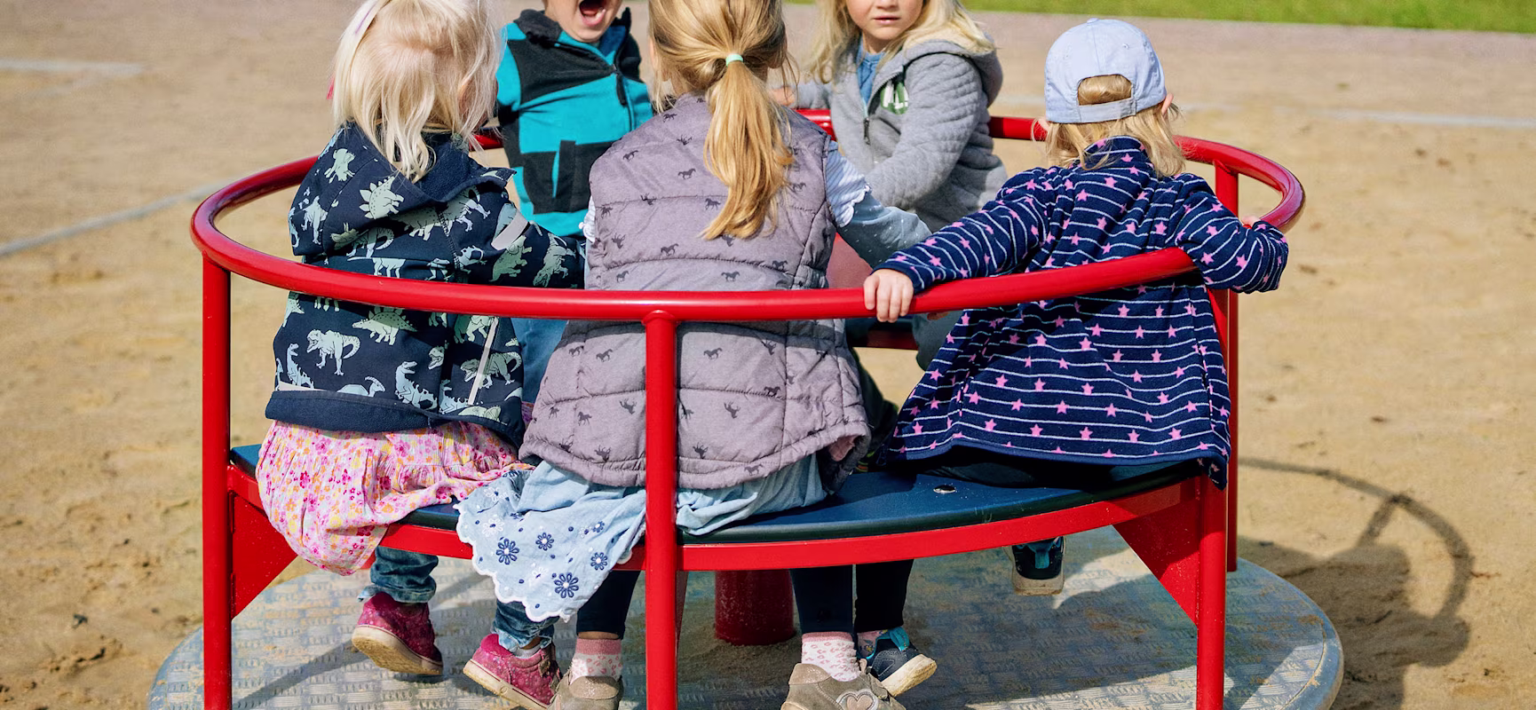 Kitakinder spielen auf einem Spielplatzkarussell in Ihlow, Deutschland