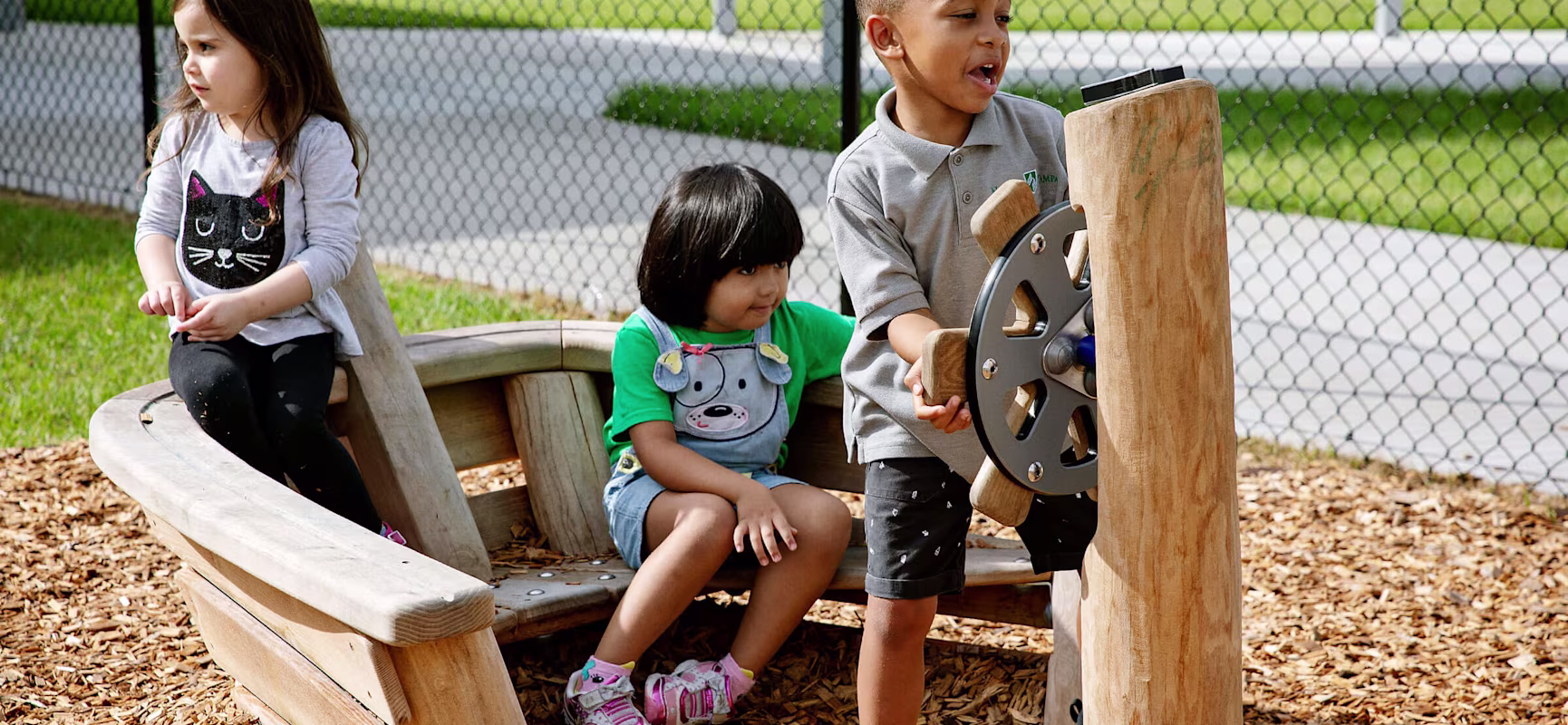 Kinder in einem Spielplatzboot aus Holz