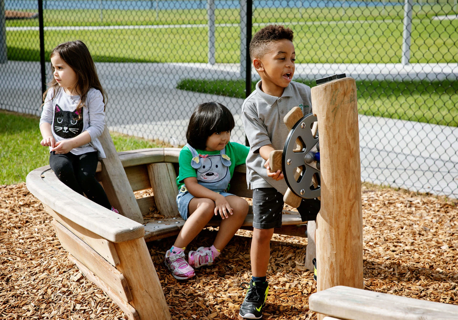 Children playing on a wooden playground boat.