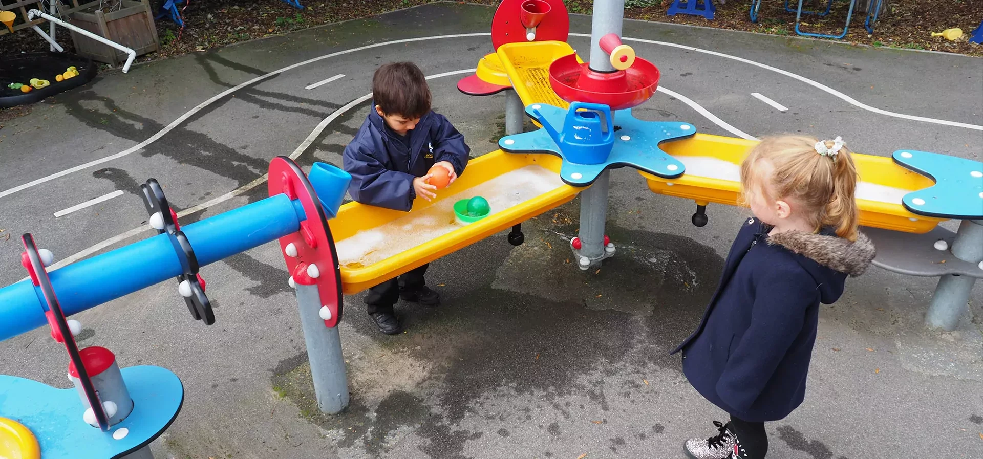 Kinder die mit einer Wasserspielanlage im Kindergarten spielen