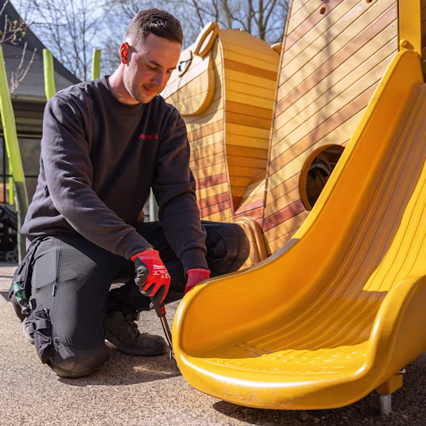 KOMPAN employee working on installing a playground slide