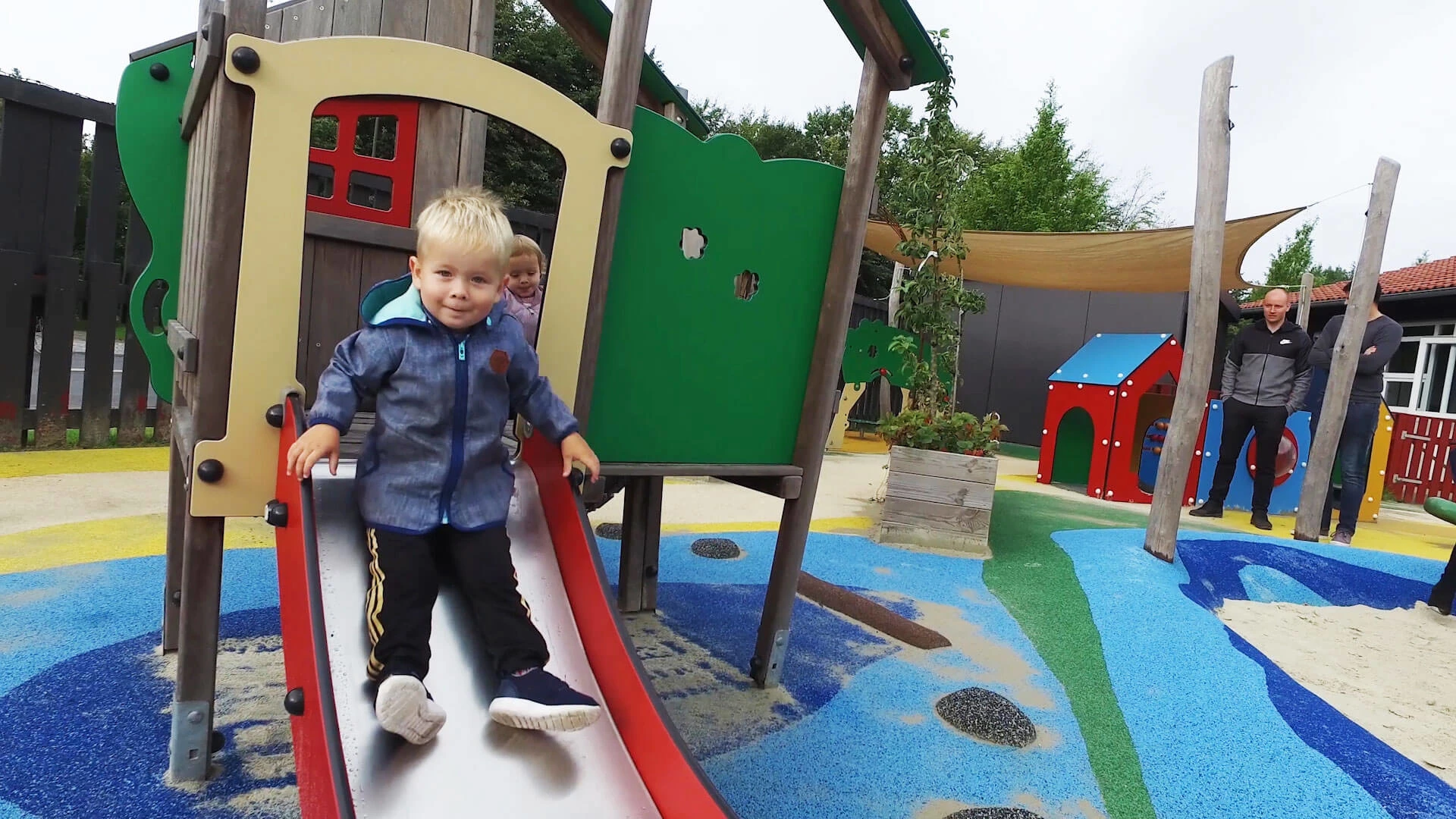 Child in kindergarten sliding down a slide on toddler equipment