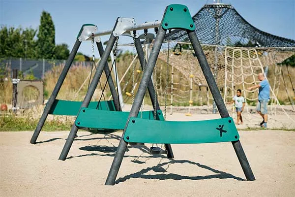A sustainably conscious playground swing set with posts made from recycled materials