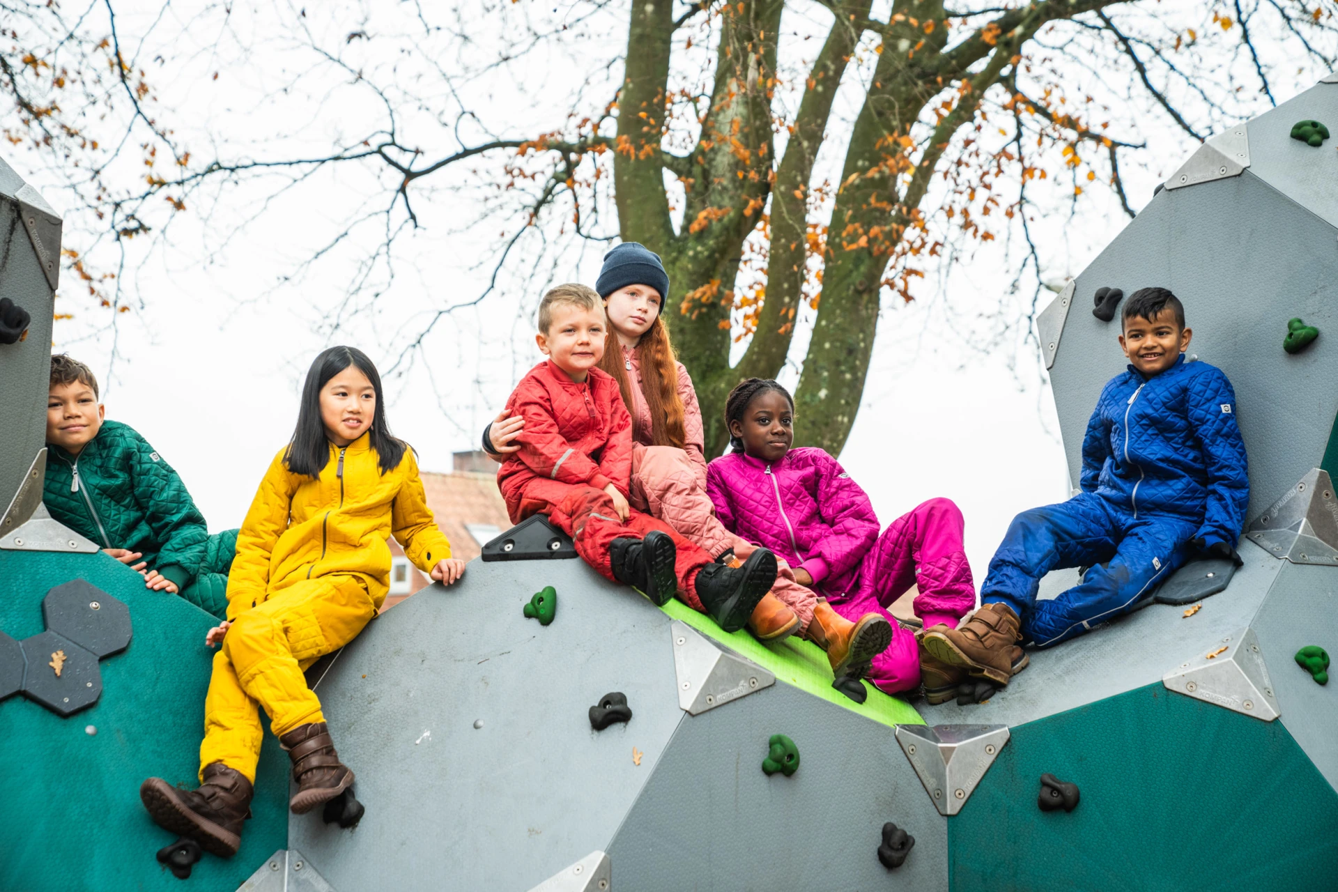 six enfants assis sur une structure d'escalade dans une aire de jeux