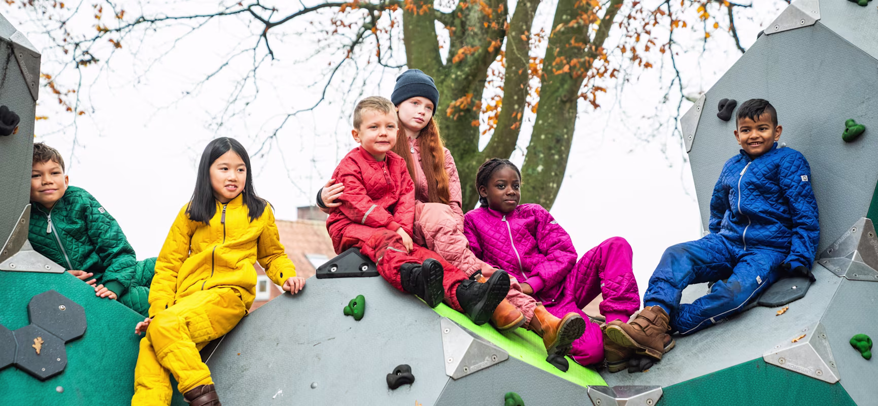 six enfants assis sur une structure d'escalade dans une aire de jeux