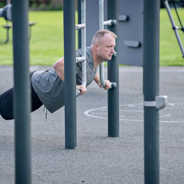 man som gör armhävningar på utomhusutrustning för callisthenics