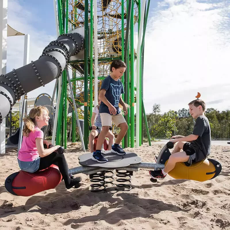 children in a park playing on a seesaw playground equipment