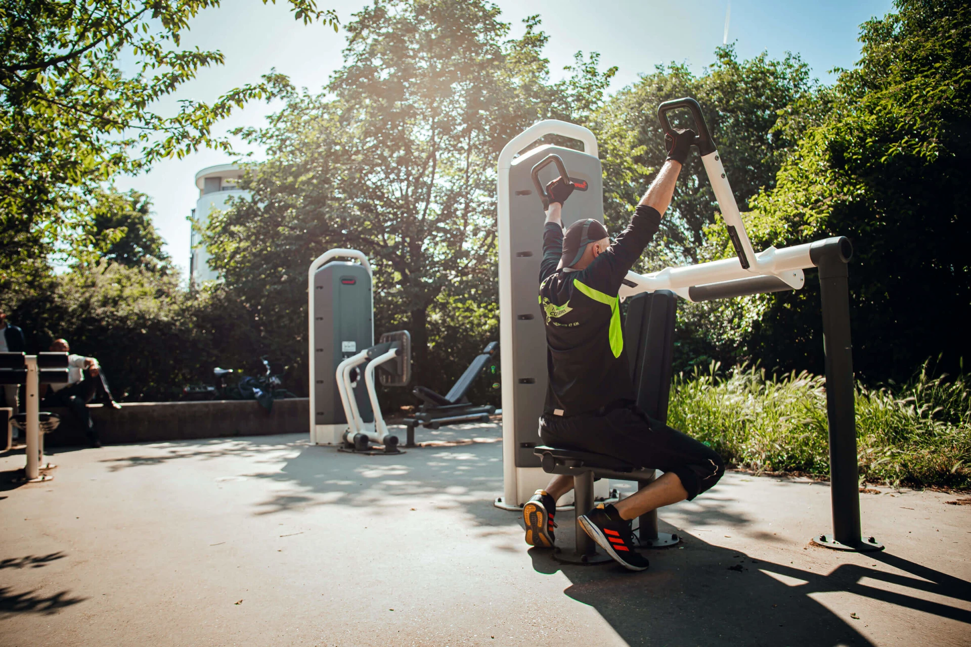 Un homme s'entraînant sur un appareil de musculation en plein air dans un parc.