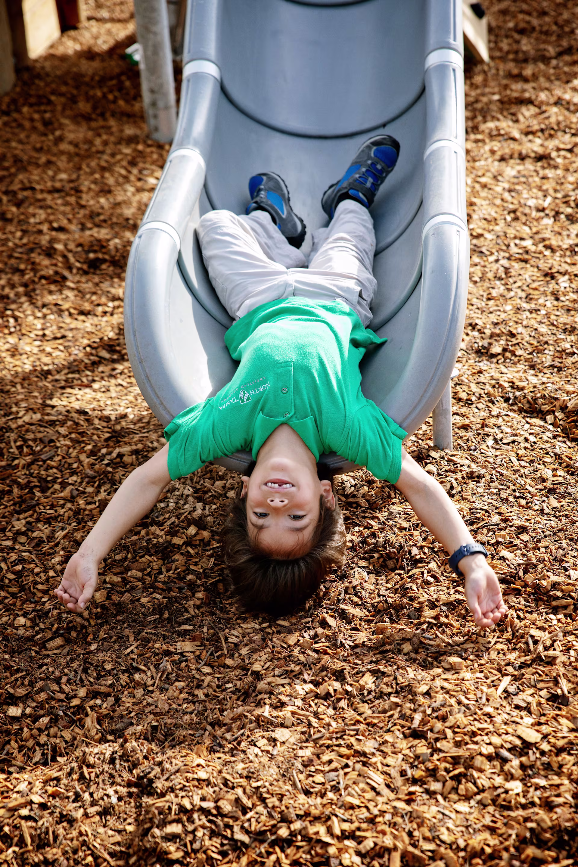Child playing on a playground slide by KOMPAN