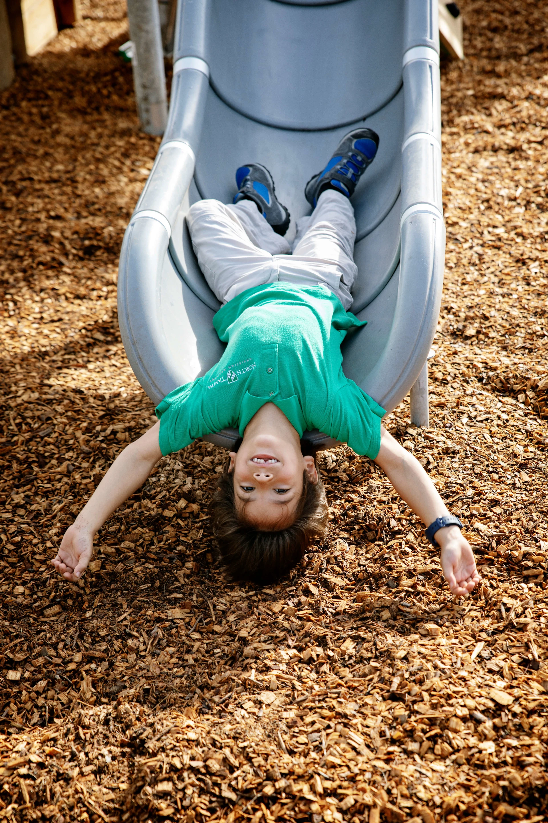 Child playing on a playground slide by KOMPAN