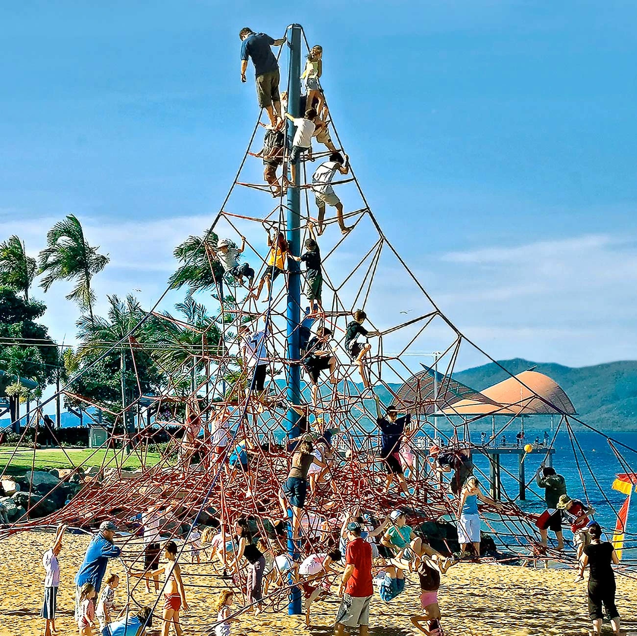 children playing on a large corocord rope playground climbing pyramid
