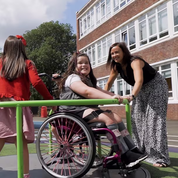 坐在轮椅上的男孩与女护工在操场上玩耍