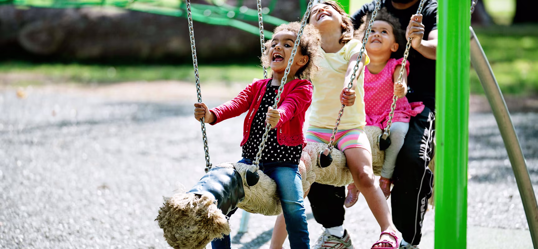 3 Children and their father on a coconut pendulum swing laughing