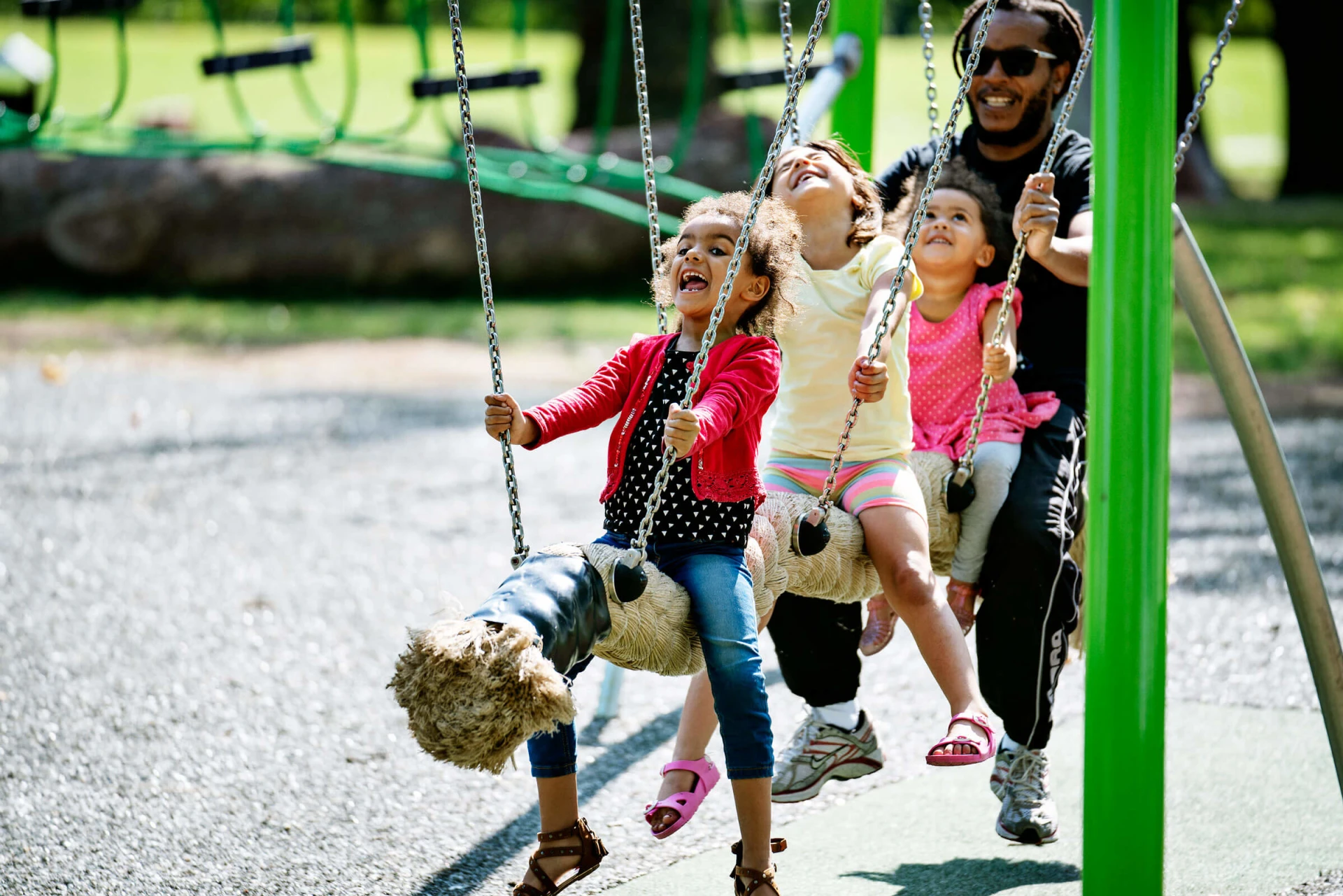 3 Children and their father on a coconut pendulum swing laughing