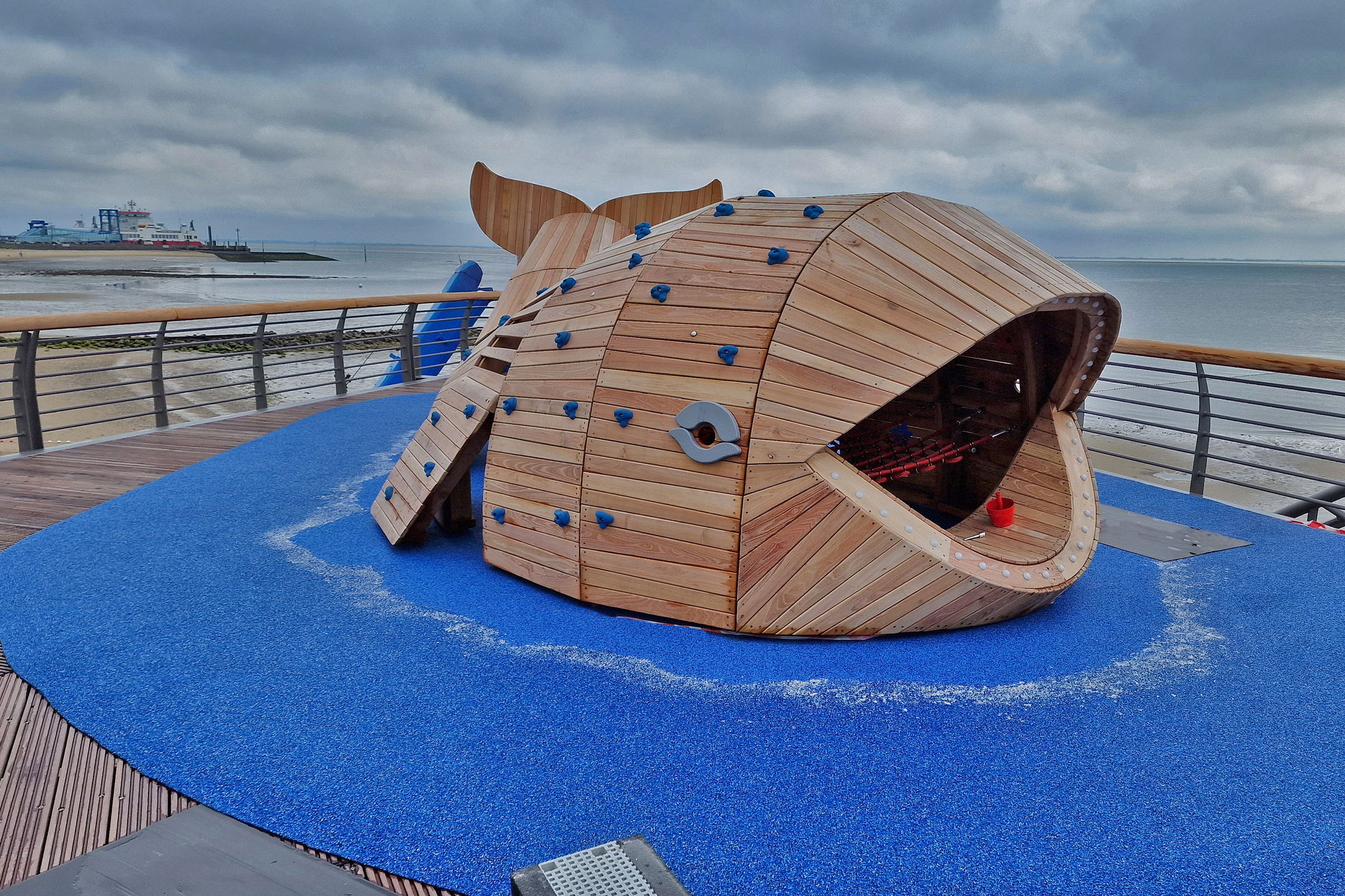 Spielgerät aus Robinienholz in Form eines Wals auf einer Seebrücke