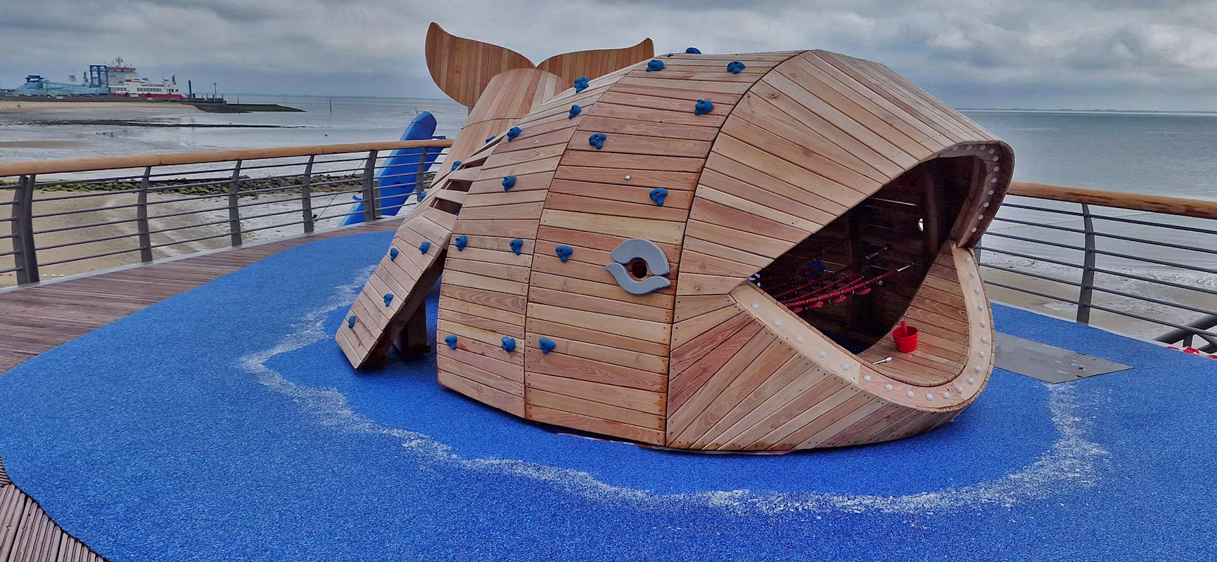 Spielgerät aus Robinienholz in Form eines Wals auf einer Seebrücke