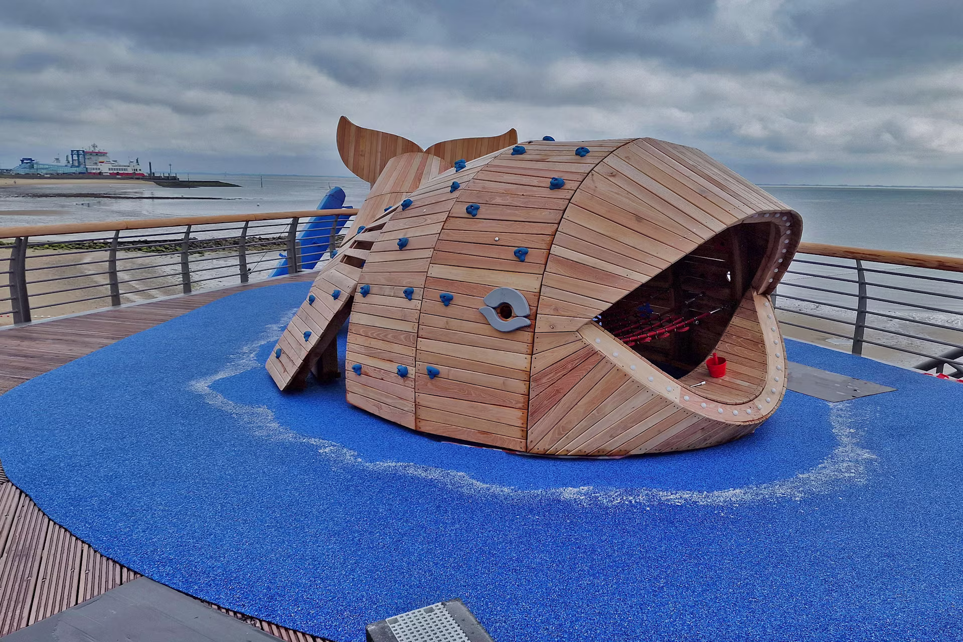 Spielgerät aus Robinienholz in Form eines Wals auf einer Seebrücke