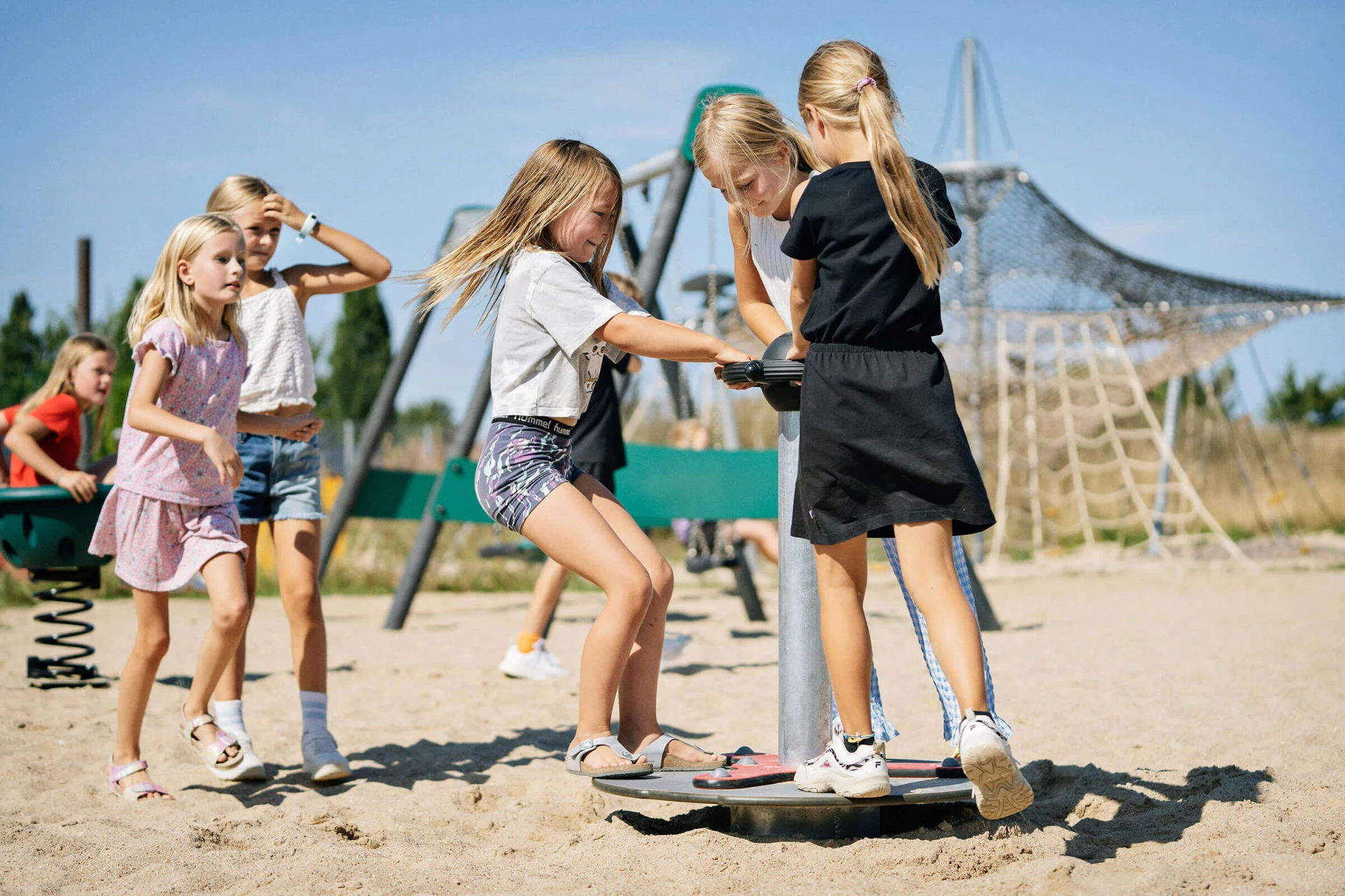 Piger, der har det sjovt på scooterkarrusellen på en KOMPAN-legeplads