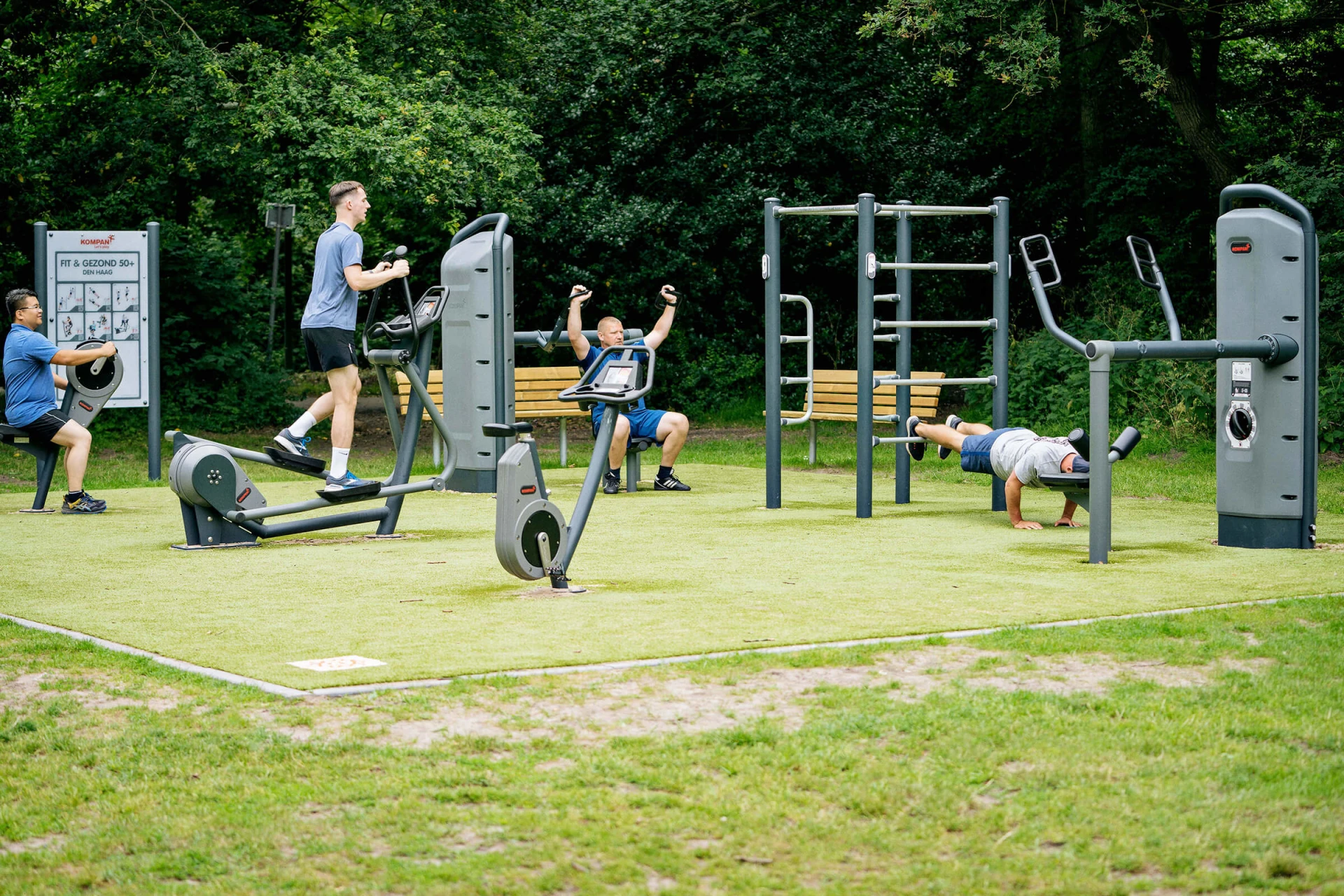 People working out at an outdoor fitness area, using outdoor strength and cardio machines