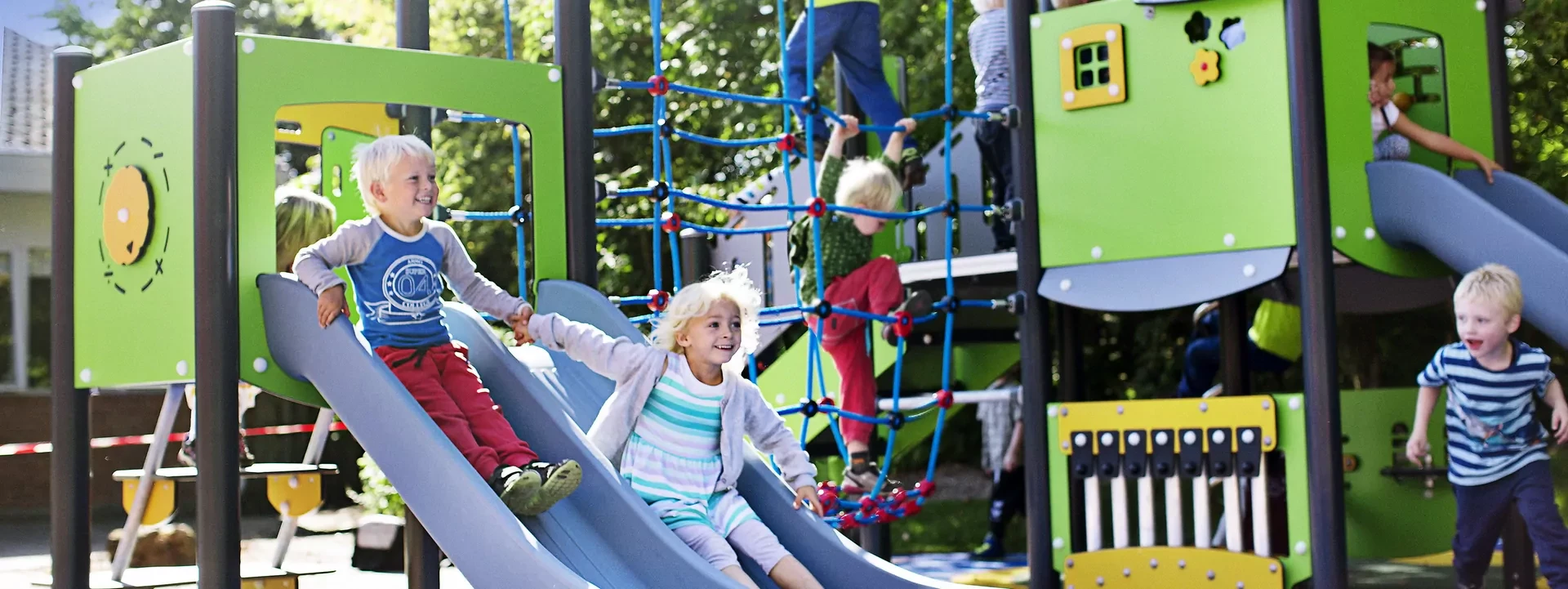 Children having fun sliding and climbing on a MOMENT play system