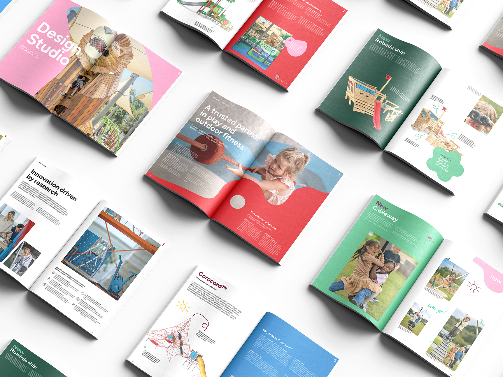 Colorful open brochures on a white surface showing playground equipment, children playing, and design studio layouts.
