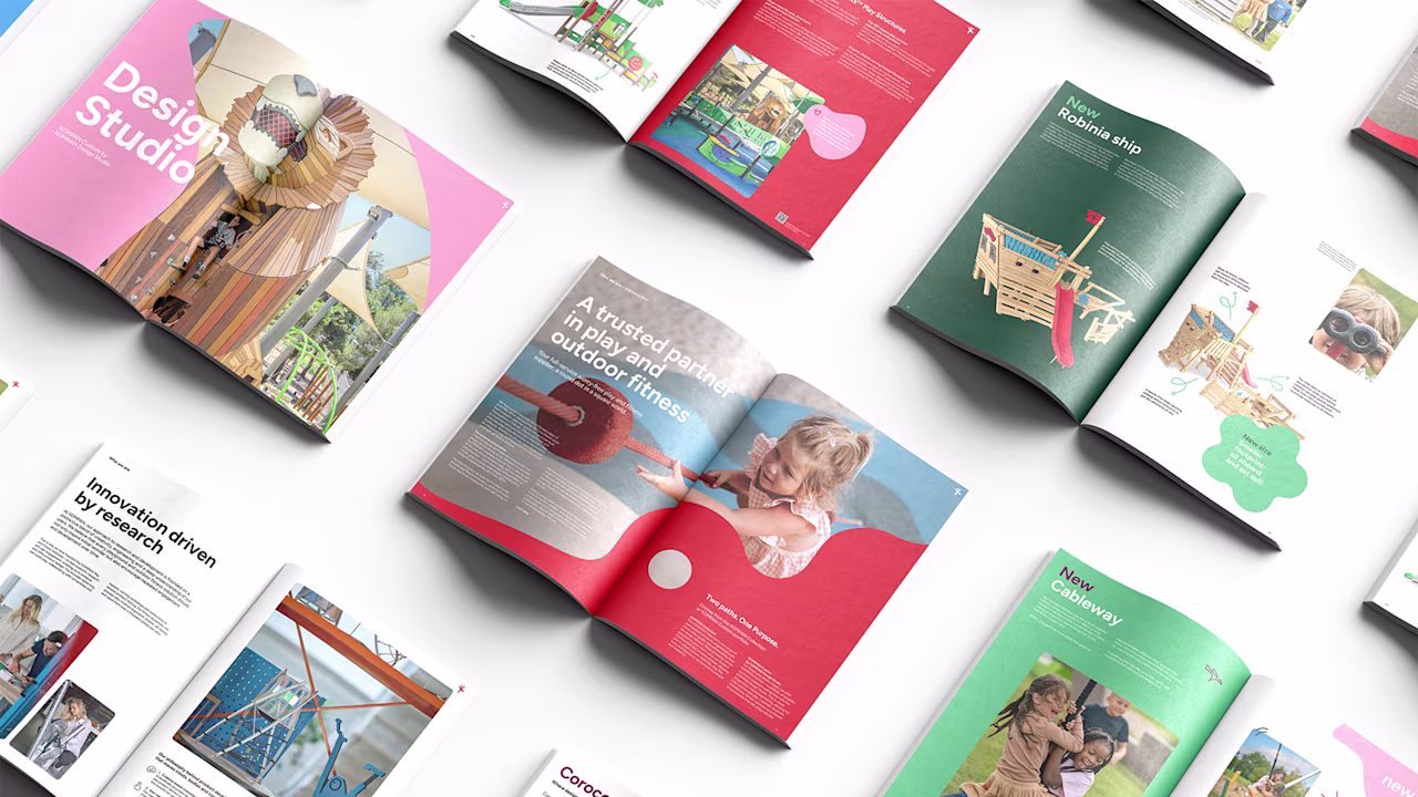 Colorful open brochures on a white surface showing playground equipment, children playing, and design studio layouts.