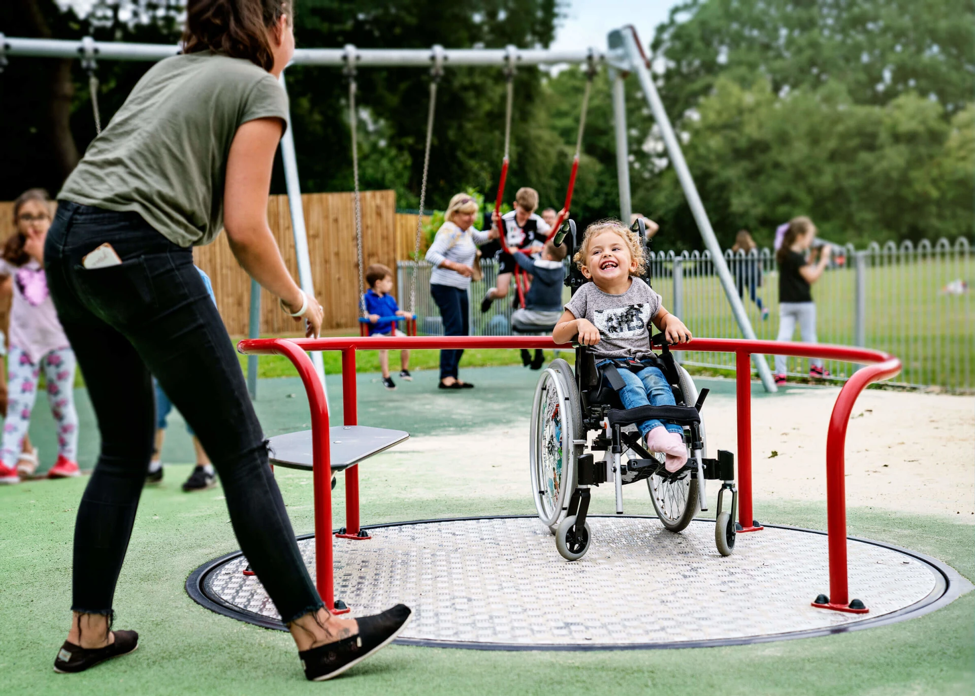 Girl in wheelchair on an inclusive playground carousel with easy access 