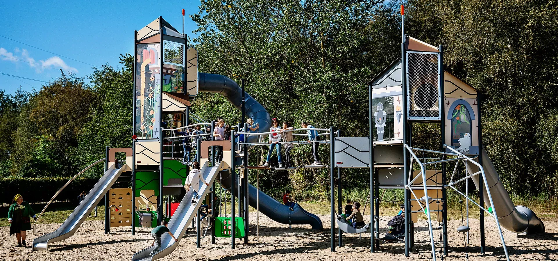 pääkuva suuresta leikkijärjestelmästä puistossa, jossa koululaiset leikkivät