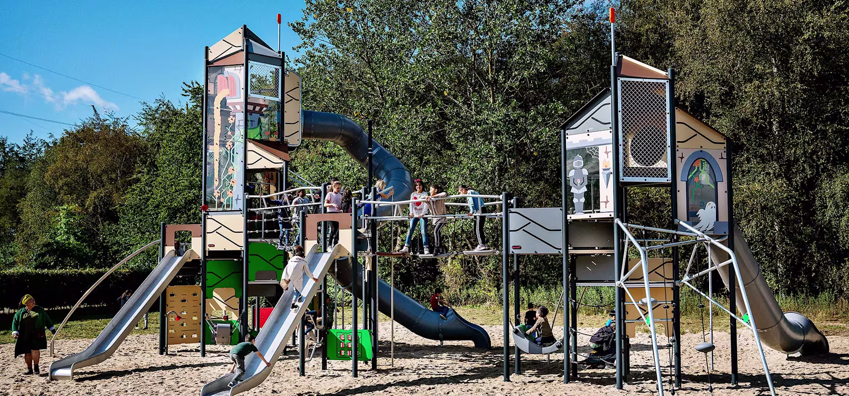 hero image of large play system in a park with school children playing