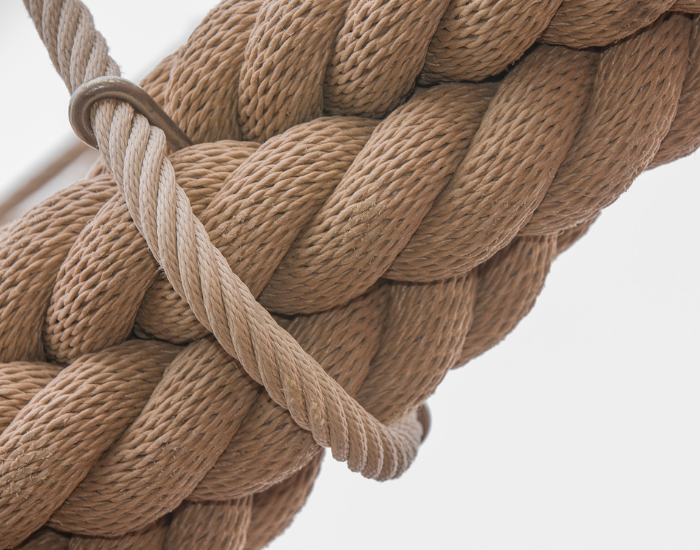 Close-up of thick braided tan rope with a smaller rope looped around it against a plain light background.