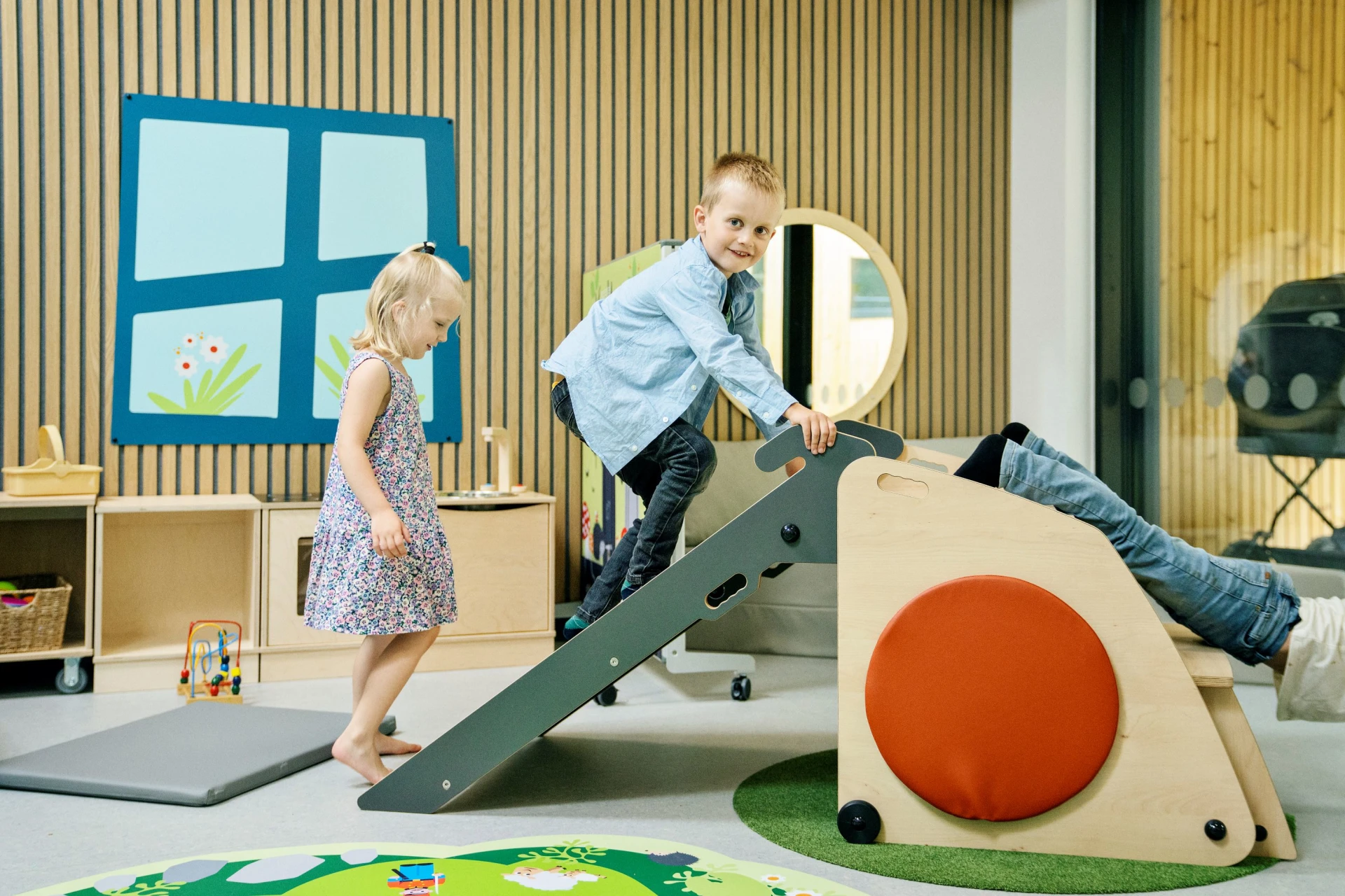 En dreng og to piger leger på indendørs legemoduler