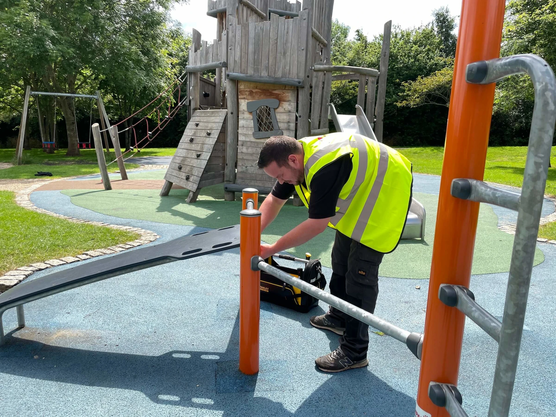 Un hombre arregla un tobogán en un parque infantil