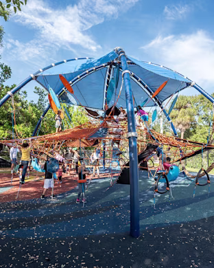Many children playing on a high-capacity playground climbing structure at Anderson Playground in Tampa, Florida