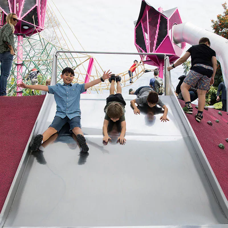 children sliding down a commercial playground slide in australia